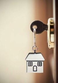 Llave-de-la-casa-en-un-llavero-de-plata-en-forma-de-casa-en-la-cerradura-de-una-puerta.jpg